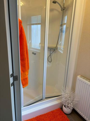 a bathroom with a shower with an orange towel at Orange Caprice Escape, Church Farm in Pagham