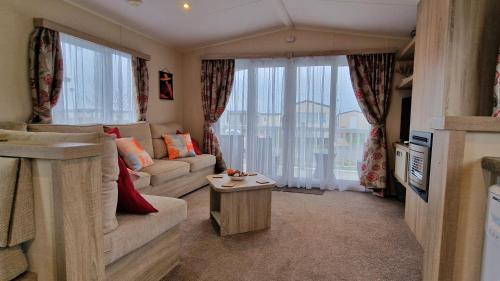 a living room with a couch and a large window at Orange Caprice Escape, Church Farm in Pagham