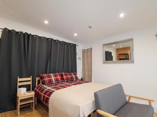 a bedroom with a bed and a chair and a mirror at Faodail Studio in Portree
