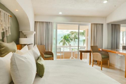 a hotel room with a bed and a table and chairs at Puerto Aventuras Hotel & Beach Club in Puerto Aventuras