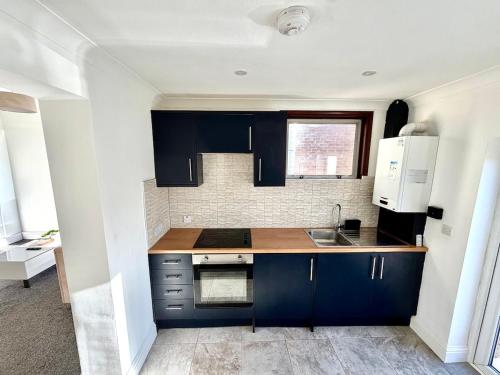 a kitchen with blue cabinets and a sink at Private Apartment Free parking Gatwick Airport - One bedroom- One sofa Bed in Horley