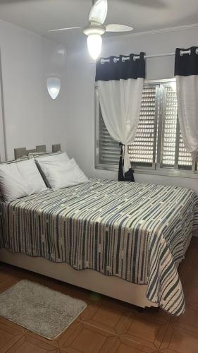 a bedroom with a bed and a window with curtains at Apto completo,1 dorm, pé na areia na Cidade Praia Grande, praia mirim in Praia Grande
