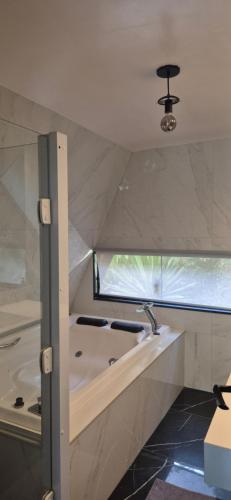 a bathroom with a tub and a sink at Chalé Suíço com Jacuzzi in Marechal Floriano