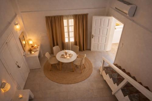 a dining room with a white table and chairs at Noème Santorini in Perissa