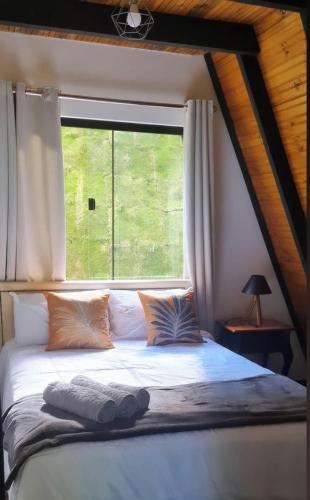 a bed in a room with a large window at Chalé Suíço com Jacuzzi in Marechal Floriano
