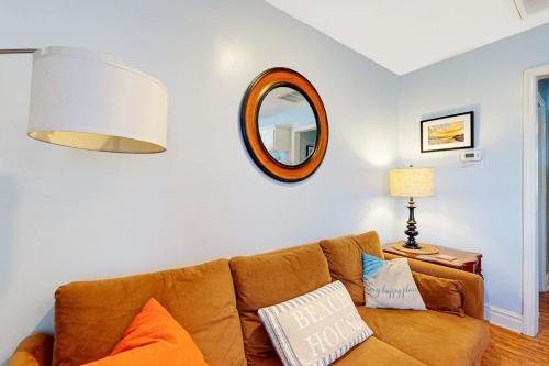 a living room with a brown couch and a mirror at Oceanbound in Folly Beach
