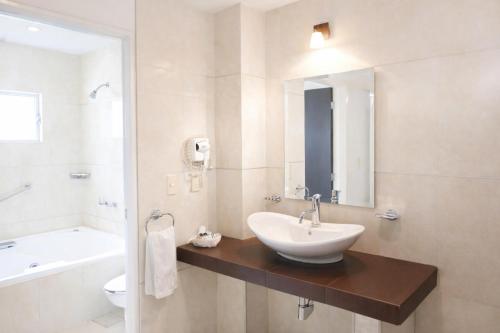 a bathroom with a sink and a tub and a toilet at Hotel Acámbaro Plaza in Acámbaro