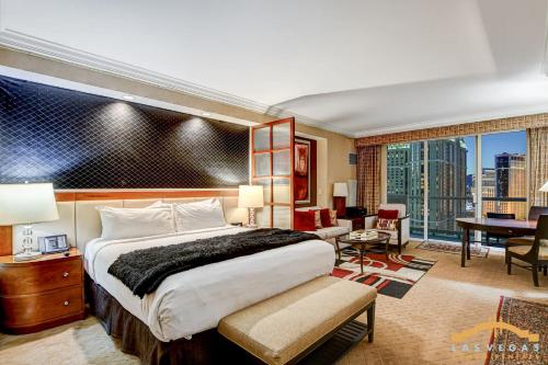 a hotel room with a large bed and a desk and a desk at MGM Signature-22-615 Strip View Balcony Studio in Las Vegas