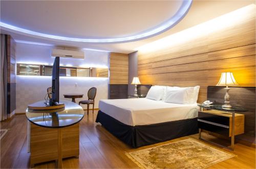 a hotel room with a bed and a desk with a television at Recanto Cataratas - Thermas, Resort e Convention in Foz do Iguaçu