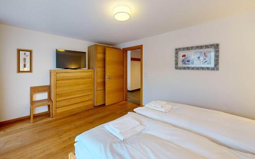 a bedroom with two beds and a television in it at ZermHaus - in the village center - very comfortable in Zermatt