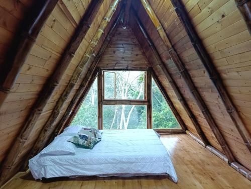 a bed in a wooden room with a window at Alma Silvestre in Puerto Triunfo