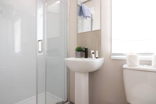 a white bathroom with a sink and a shower at The Forest Lodge, Glen Eagles. in Auchterarder
