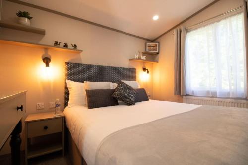 a bedroom with a large white bed with a window at The Forest Lodge, Glen Eagles. in Auchterarder