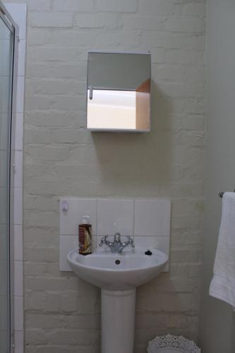 a white bathroom with a sink and a mirror at Cozy and Central Bachelor Flat in Wellington