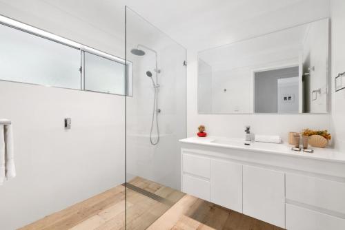 a white bathroom with a shower and a sink at Lucis Beach Retreat in Coolum Beach