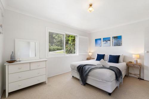 a white bedroom with a bed and a window at Lucis Beach Retreat in Coolum Beach