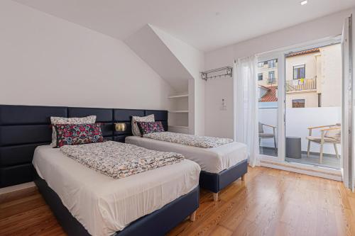 two beds in a small room with a window at Cortes Apartment in Lisbon Historic Neighborhood in Lisbon