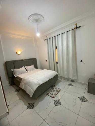 a bedroom with a bed and a tiled floor at VVVIP lita Résidence in Ekoumdoum