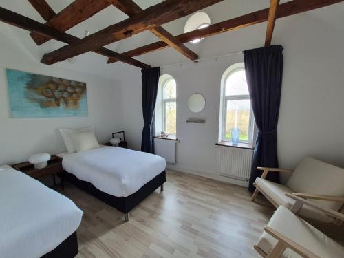 a bedroom with two beds and a couch and two windows at Søndergaarden in Øster Ulslev