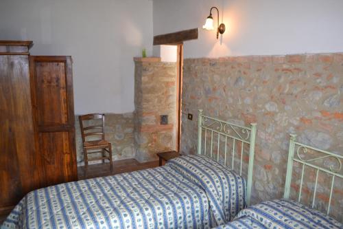 a bedroom with two beds and a chair in it at Agriturismo Nestore in Nestore