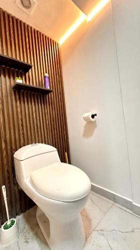 a bathroom with a white toilet and a wooden wall at Suite con vista al mar Acapulco in Acapulco