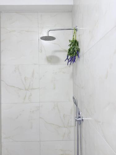a white tiled shower with a plant on the wall at 13 Daily apartments in Tirana