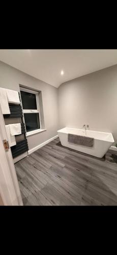 a white bathroom with a tub and a window at The Arch apartment in Bangor