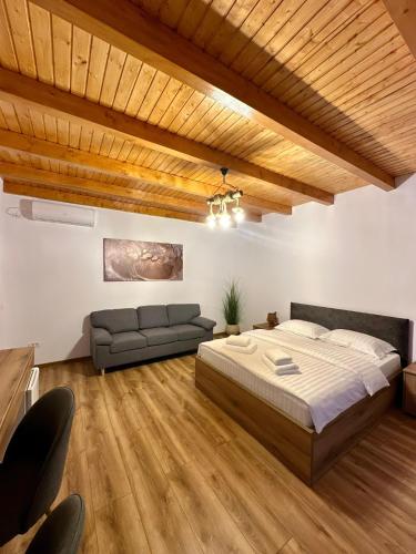a bedroom with a large bed and a couch at Casa Sima 2 in Curtea de Argeş
