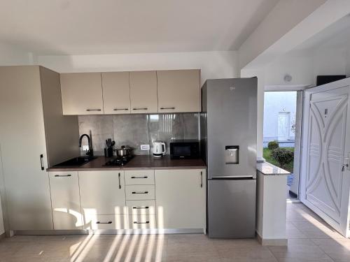 a kitchen with white cabinets and a stainless steel refrigerator at Studio in 2 Mai,Quiet,Spacious,Garden,Separate Bedroom - Donilads Properties - Home Everywhere in 2 Mai