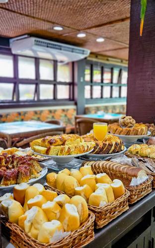 a buffet filled with different types of food on plates at Hotel Nacional Inn Ubatuba - Praia das Toninhas in Ubatuba