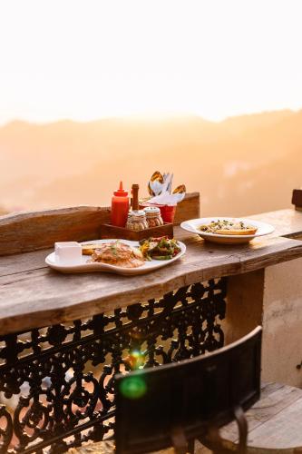 a wooden table with two plates of food on it at Hotel Willow Banks Shimla in Shimla