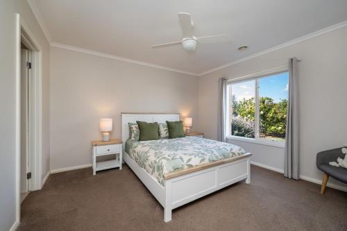 a white bedroom with a bed and a window at Parkside Breeze in Rosebud in Rosebud