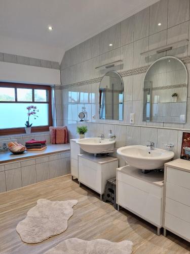 a bathroom with two sinks and two mirrors at Haus mit Seeblick in Fürstenau