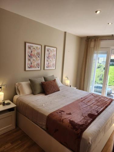 a bedroom with a large bed and a window at Apartamento Sandy - wifi, ascensor, vistas al Mar,Amplio y Acogedor in Laxe