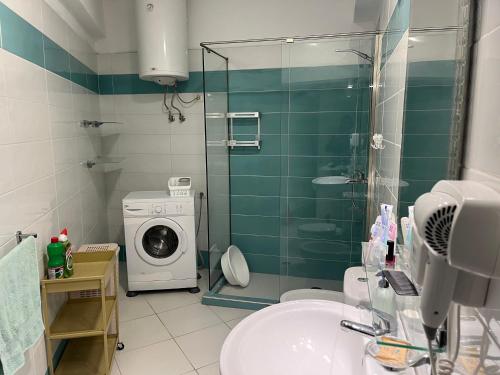 a bathroom with a sink and a washing machine at Apartment bay, Bougainville Bay Resort in Sarandë