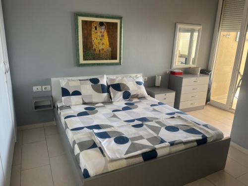 a bedroom with a bed with a blue and white comforter at Apartment bay, Bougainville Bay Resort in Sarandë