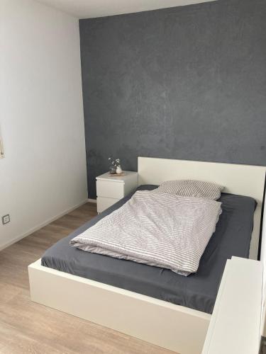 a bedroom with a white bed and a gray wall at Klein aber fein in Gaimersheim