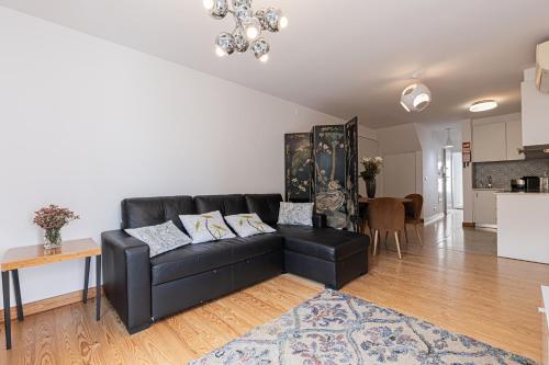a living room with a black couch and a kitchen at Barbadinhos Apartments in Lisbon Historic Neighborhood in Lisbon