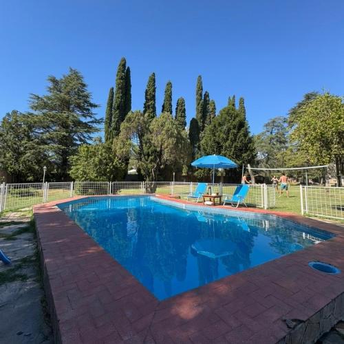 a swimming pool with two chairs and an umbrella at Arcadia entre cipreses in Pueblo Esther