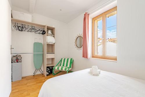 a bedroom with a bed and a window and a chair at Duplex 2chambres avec Terrasse Centre Historique in Fréjus