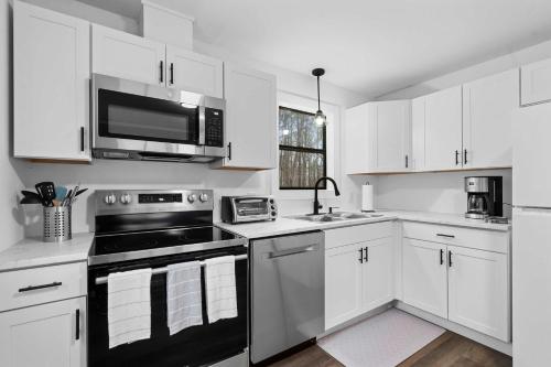 a white kitchen with a stove and a microwave at 8 Minutes to UNC - Outdoor Deck - Washer and Dryer in Chapel Hill