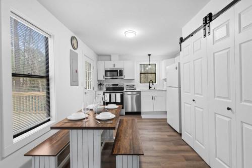 a white kitchen with a wooden table in it at 8 Minutes to UNC - Outdoor Deck - Washer and Dryer in Chapel Hill