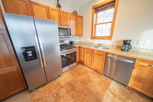 a kitchen with stainless steel appliances and wooden cabinets at Antlers Gulch 106 by SummitCove Lodging in Colorado in Keystone