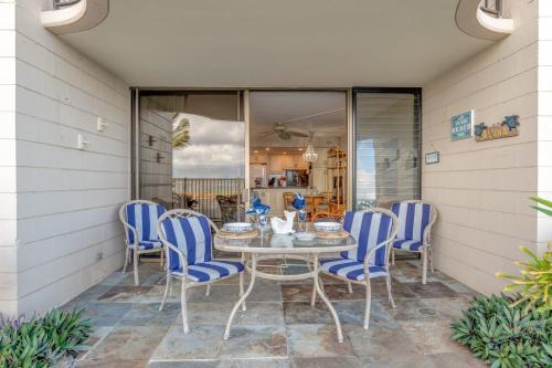 a patio with a table and blue chairs at Kahana Reef 106 in Kahana