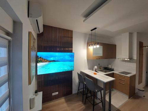 a kitchen with a television on a wall with a table at Oaza Apartmani Jakovo HERA in Jakovo