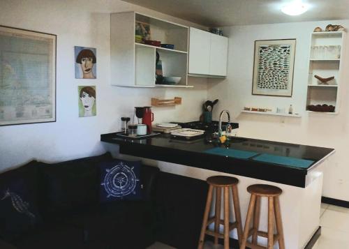 a kitchen with a black counter and two stools at Eco Paradise ART Apt.203 in Cumbuco