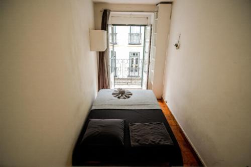 a small room with a bed and a window at Shared Apartment With Bright Private Patio in Lisboa in Lisbon