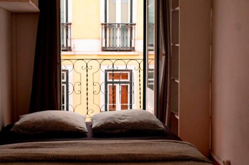 a bed with two pillows in front of a window at Shared Apartment With Bright Private Patio in Lisboa in Lisbon