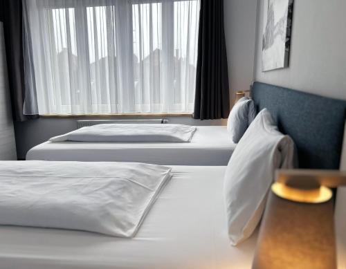 two beds in a hotel room with a window at Wellness penzion a restaurace U Gigantu in Pilsen