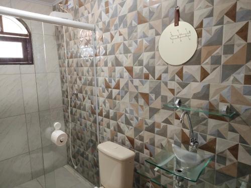 a bathroom with a toilet and a tiled wall at Oásis - Casa com Piscina e Churrasqueira in Pontal do Paraná